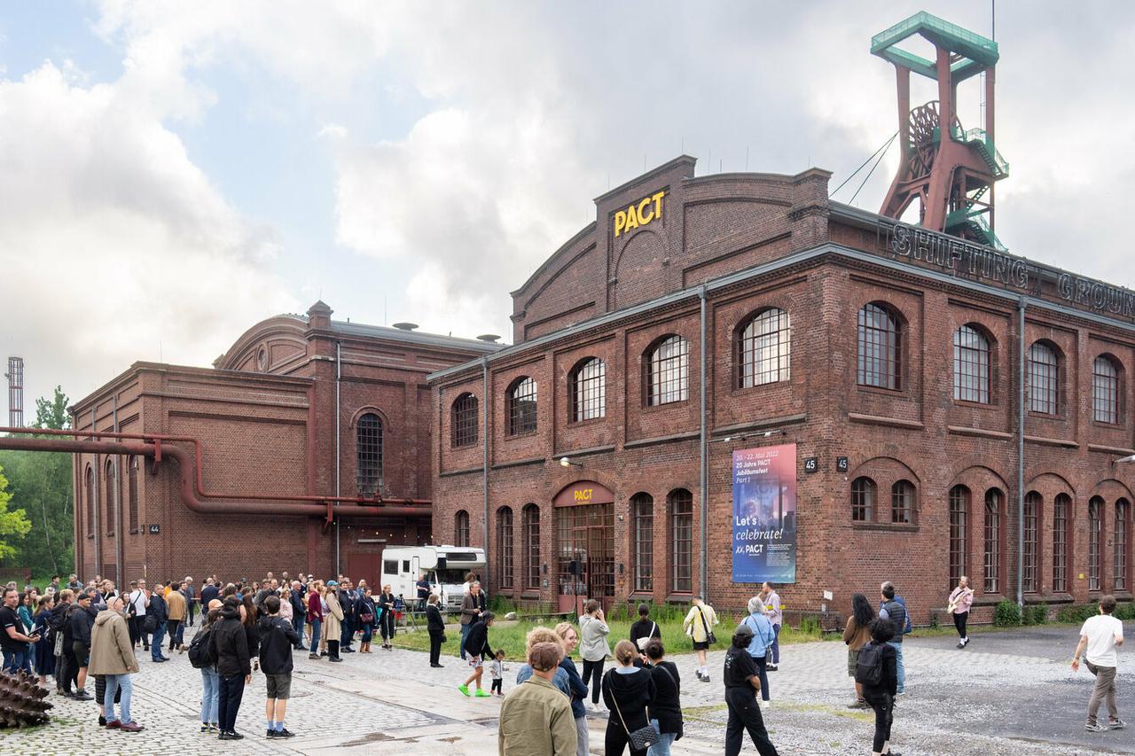 Hier sieht man ein Backsteingebäude auf einem Zechengelände mit dem PACT-Logo über dem Eingang