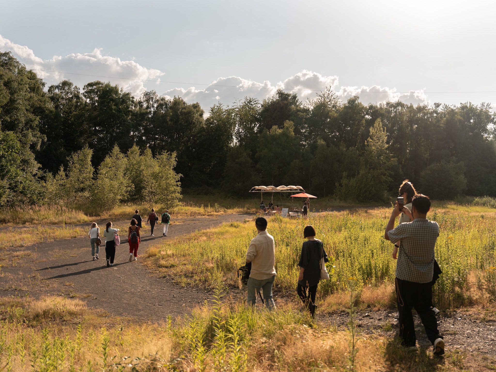 Eine Menschengruppe betritt eine karge Lichtung. Auf der Lichtung steht ein kunstvoll gestalteter Pavillon.