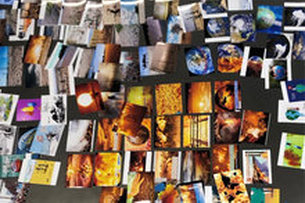 Auf Postkarten, die am Boden liegen, sind verschiedene Motive zu sehen: der erhitzte Erdball, die Welt aus dem Weltraum, Feuer…