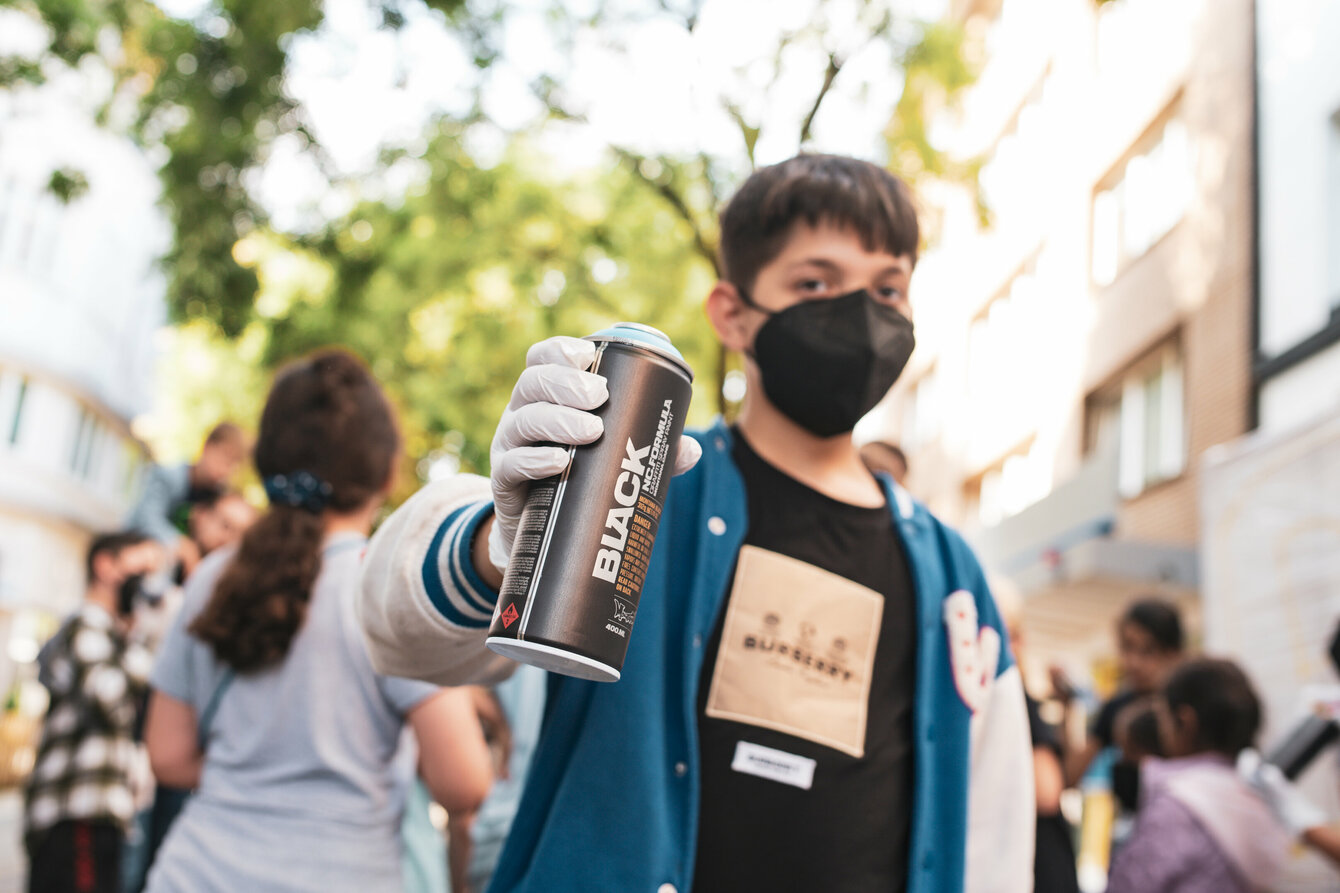 A child shows a spray can to the camera. 