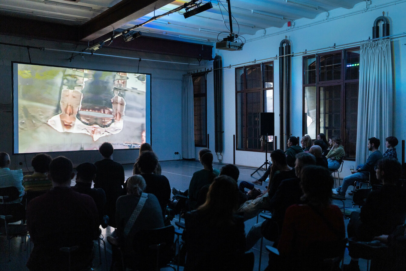 Das Publikum schaut auf eine Filmleinwand. 