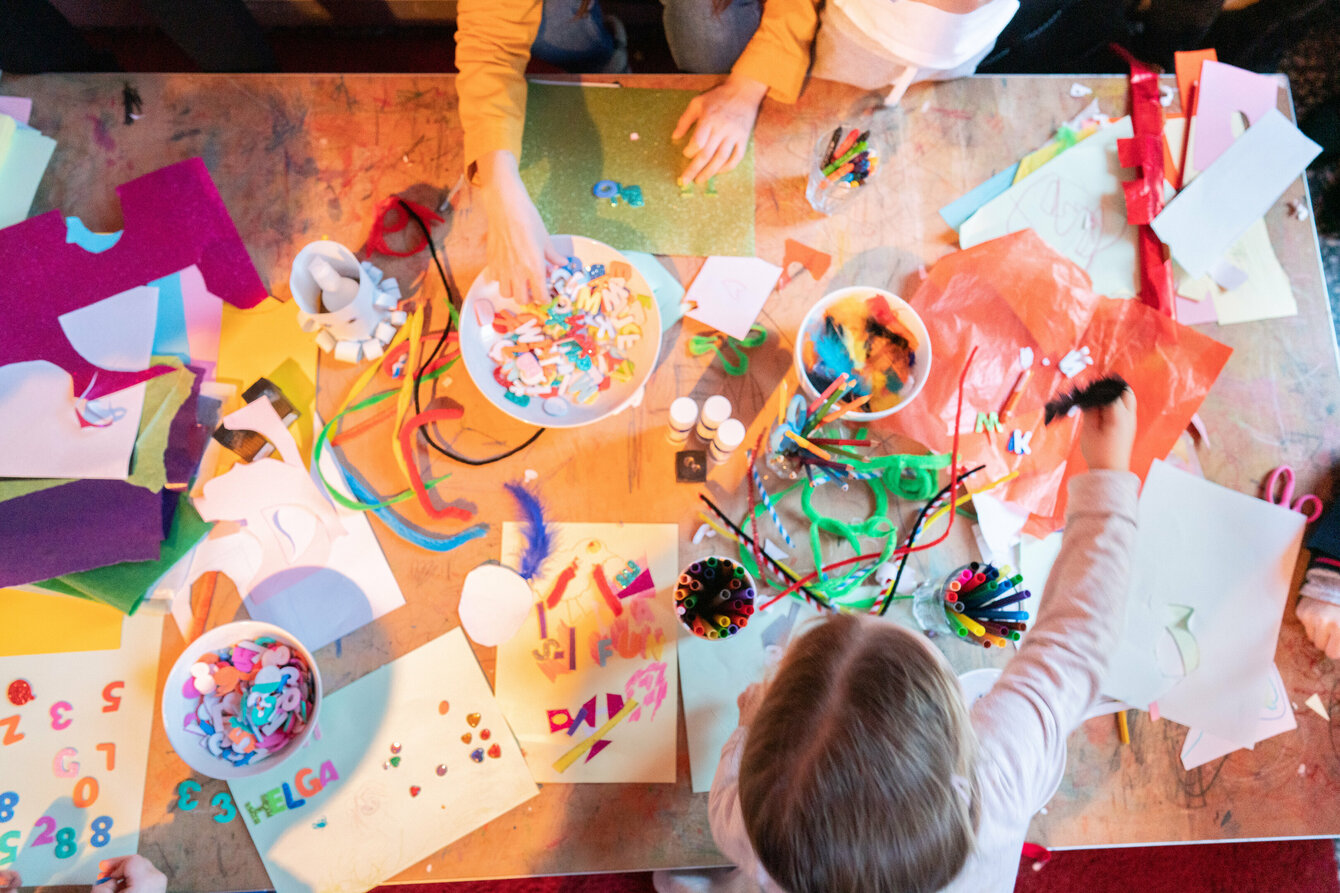 Malende Kinder die auf einem Tisch mit Stiften und Bastelutensilien hantieren