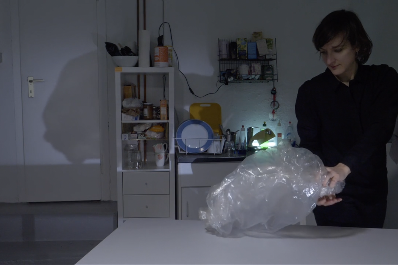 A woman standing in a kitchen handling a plastic bag