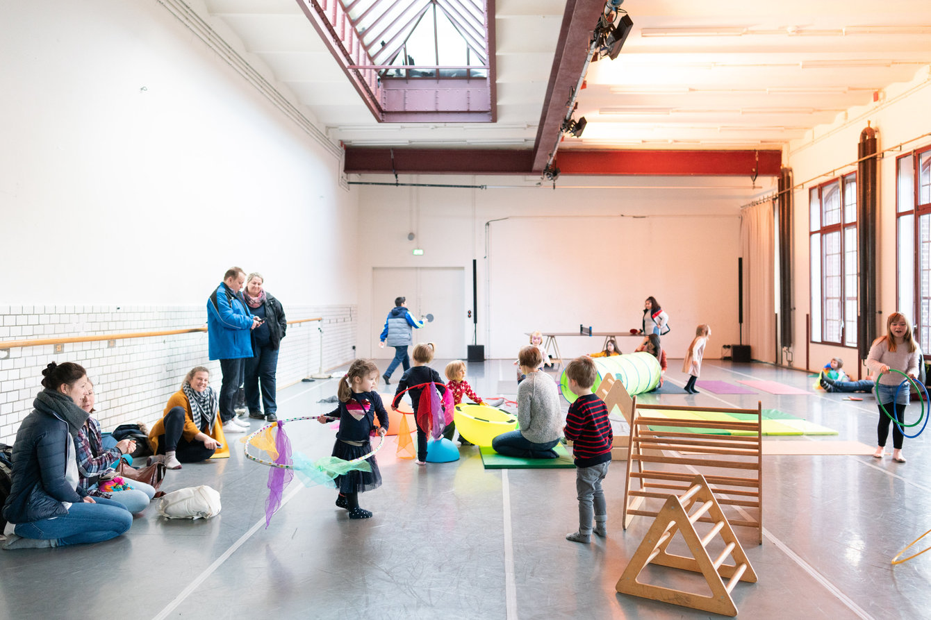 Kinder spielen in einem Tanzstudio mit Hullahupreifen, Tüchern, Matten