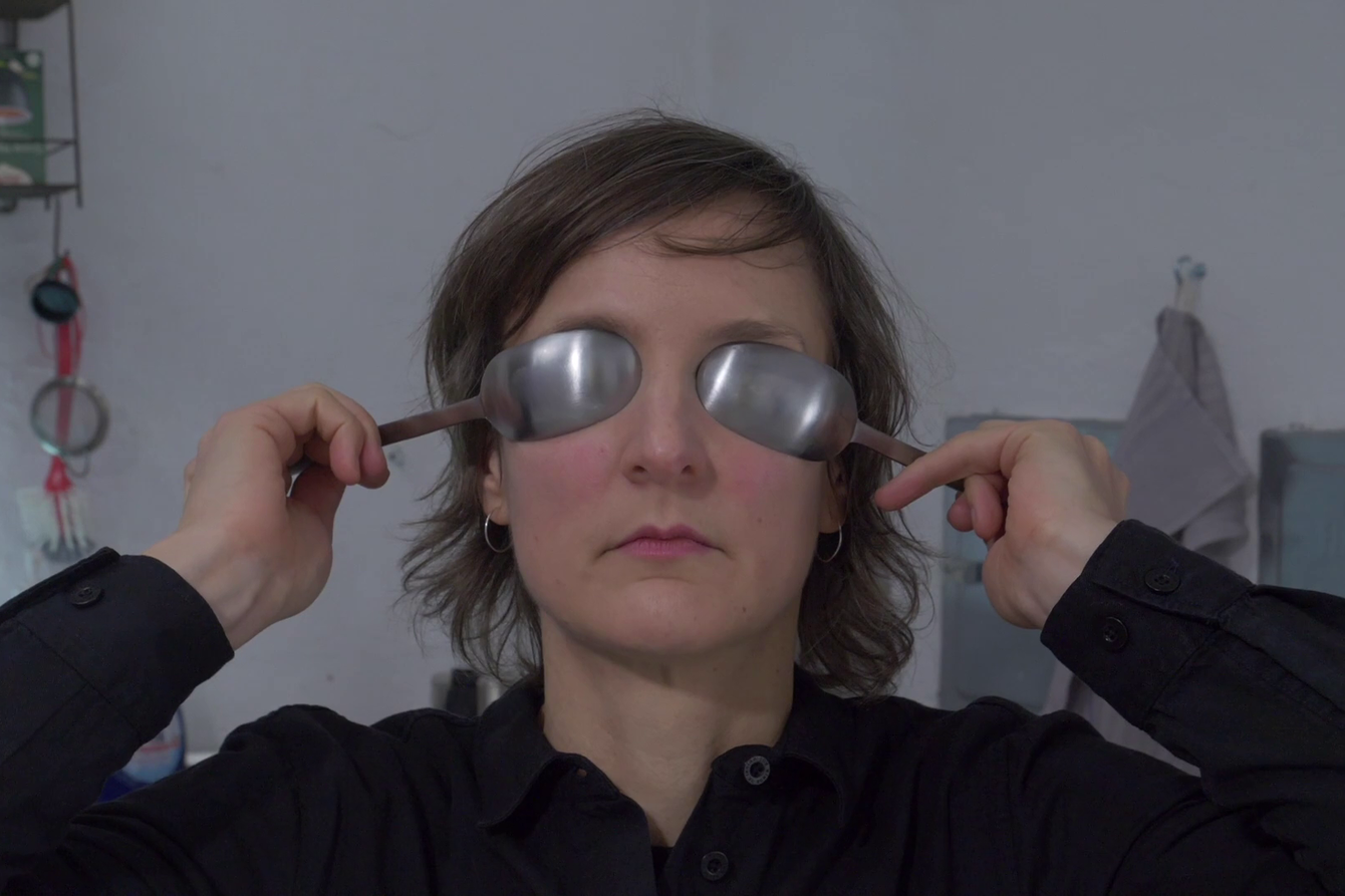 A woman covers her eyes with metal spoons