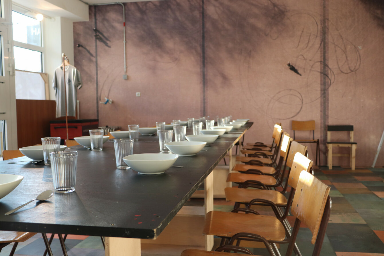 Die WerkStadt von innen. Das Foto zeigt eine lange Tafel, auf der leere Gläser, Teller und Besteck zu sehen sind.