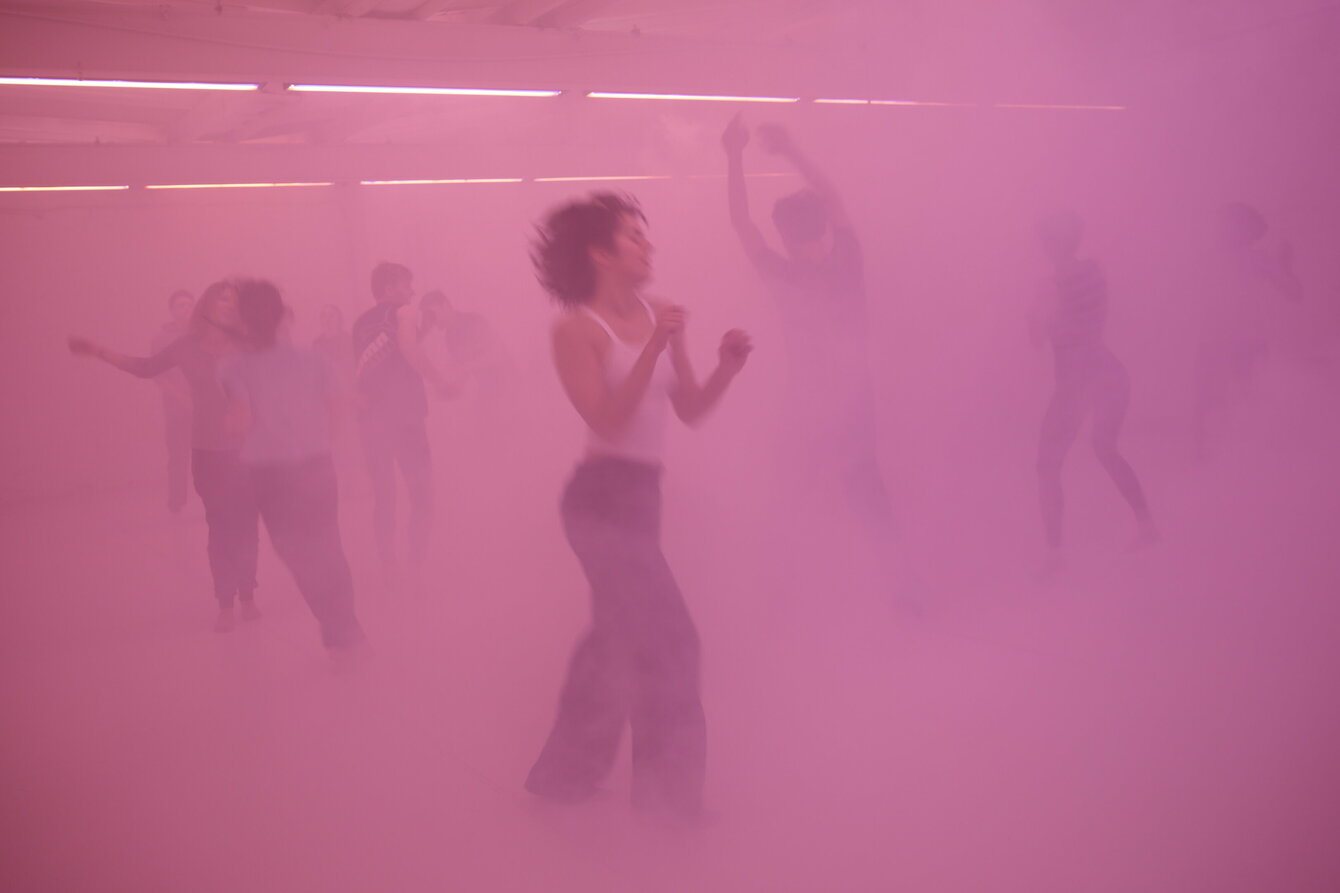 Eine Gruppe tanzender Menschen in pinkem Nebel
