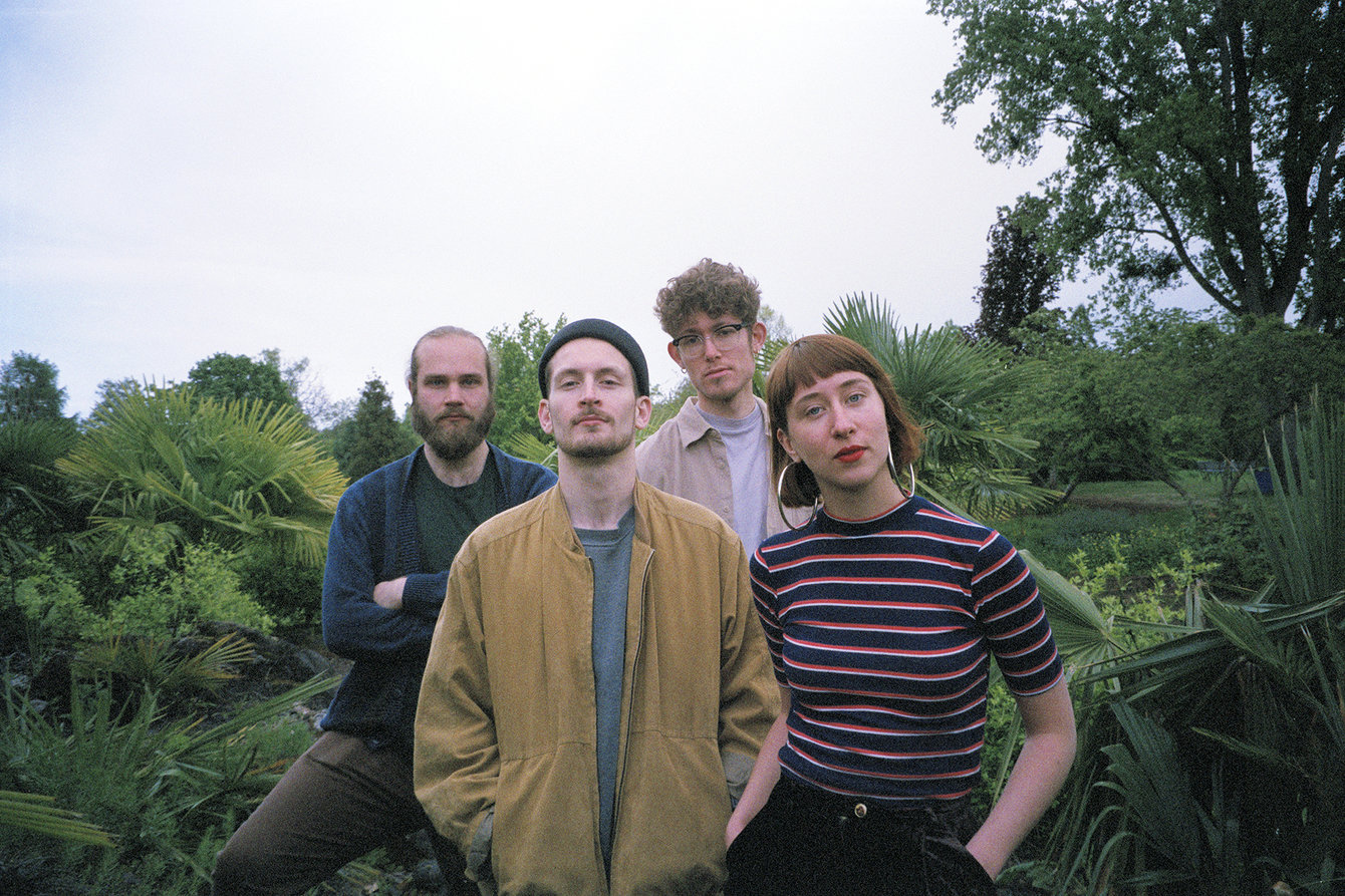 Die vier Mitglieder der Band VELOUR stehen für ein Gruppenfoto vor einem Waldstück. 