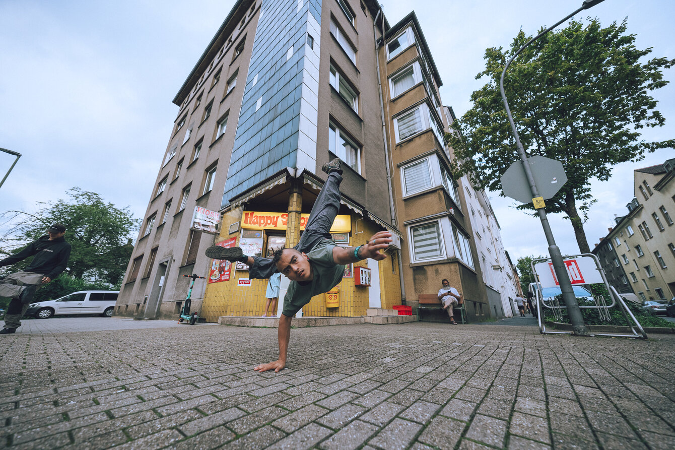 Tänzer im Handstand vor einem hohen Gebäude
