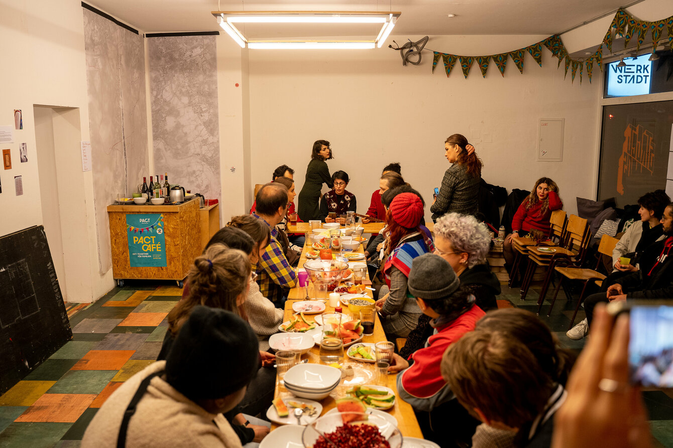 Menschen sitzen an einer langen Tafel und essen gemeinsam