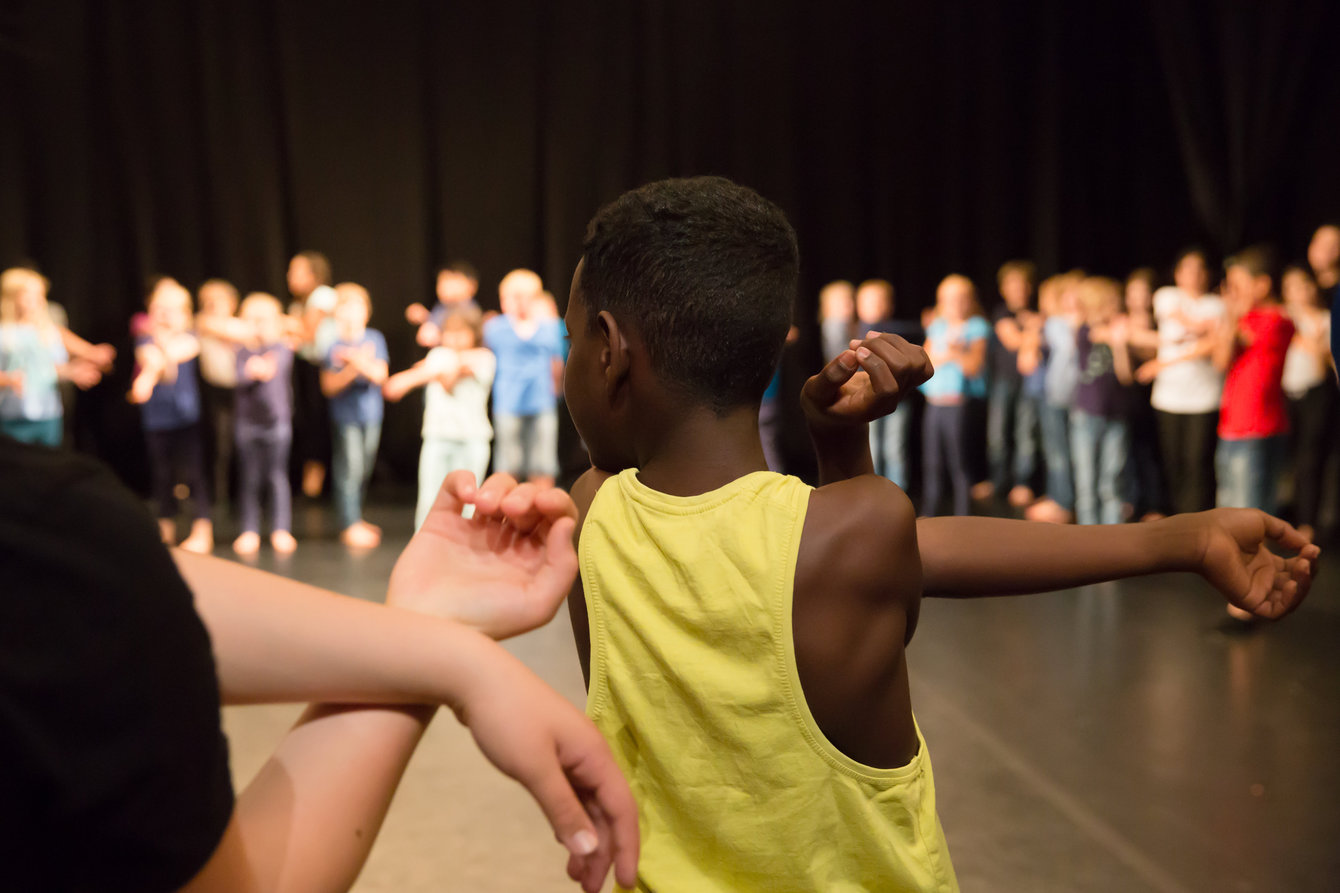 Ein junge steht in einer Kindergruppe, die Sportübungen macht