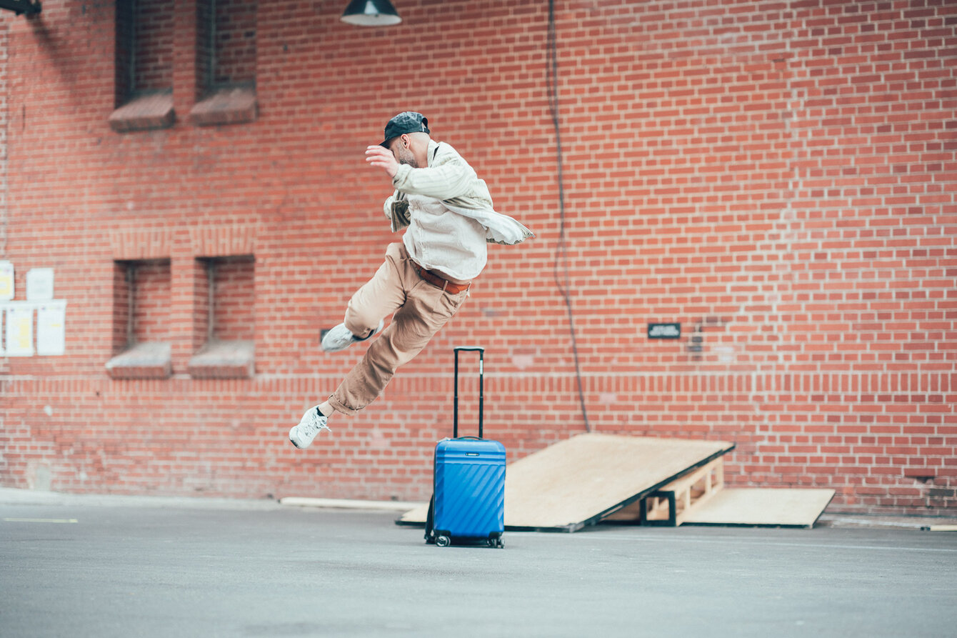 Ein Tänzer springt tanzend über einen Koffer