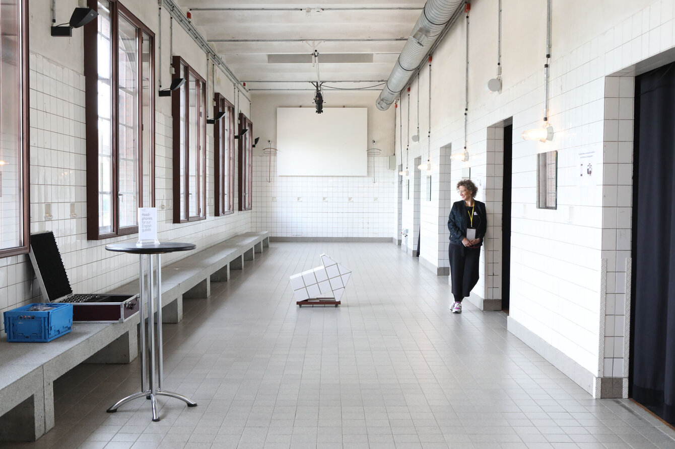 Interior view of PACT Zollverein in front of the big stage, one person is leaning against the entrance