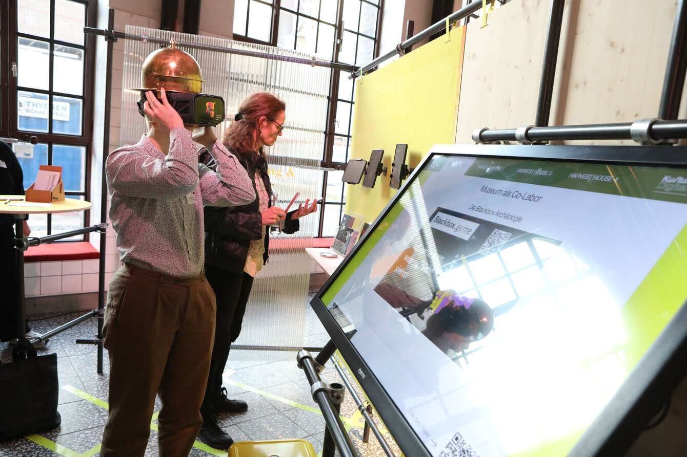 A person wears virtual reality glasses and stands in front of a screen