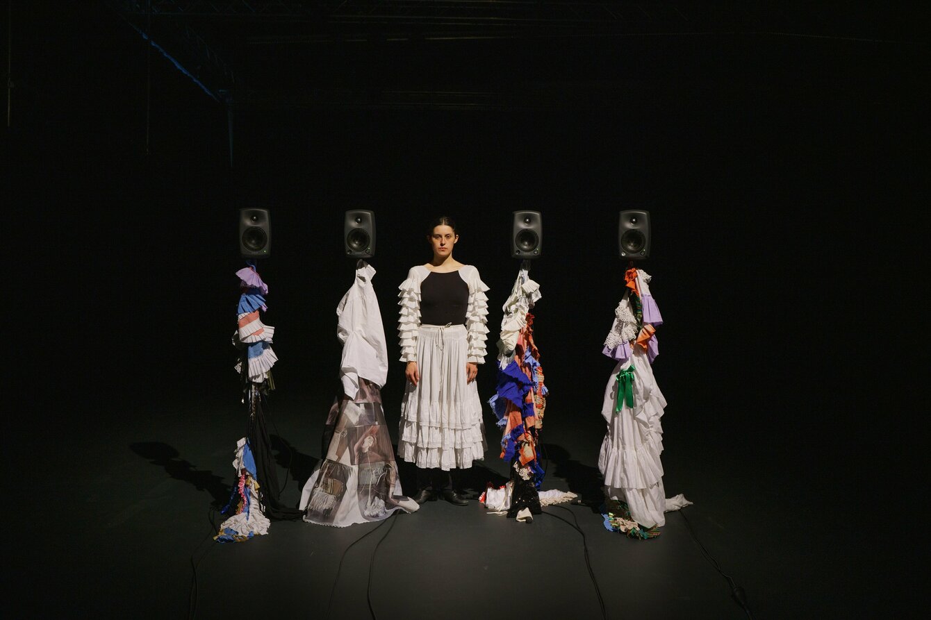 Luisa Fernanda Alfonso steht auf der Bühne zwischen Lautsprechern, die mit Stoff verkleidet sind