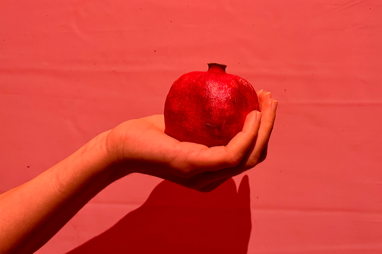 Eine Hand hält einen Granatapfel 