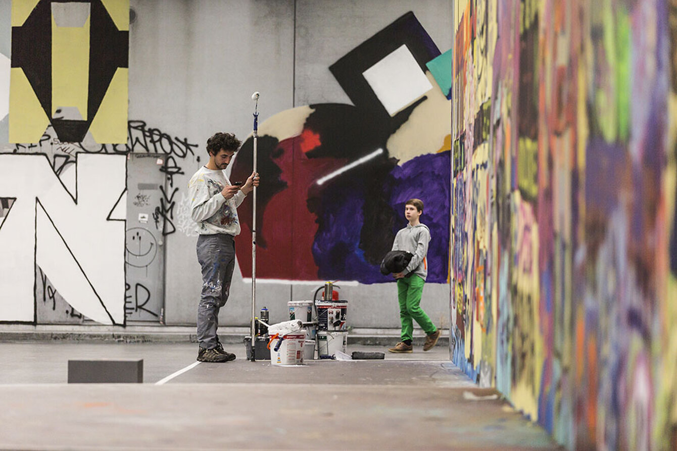 Zwei Personen stehen vor großen Wänden gefüllt mit Graffiti 