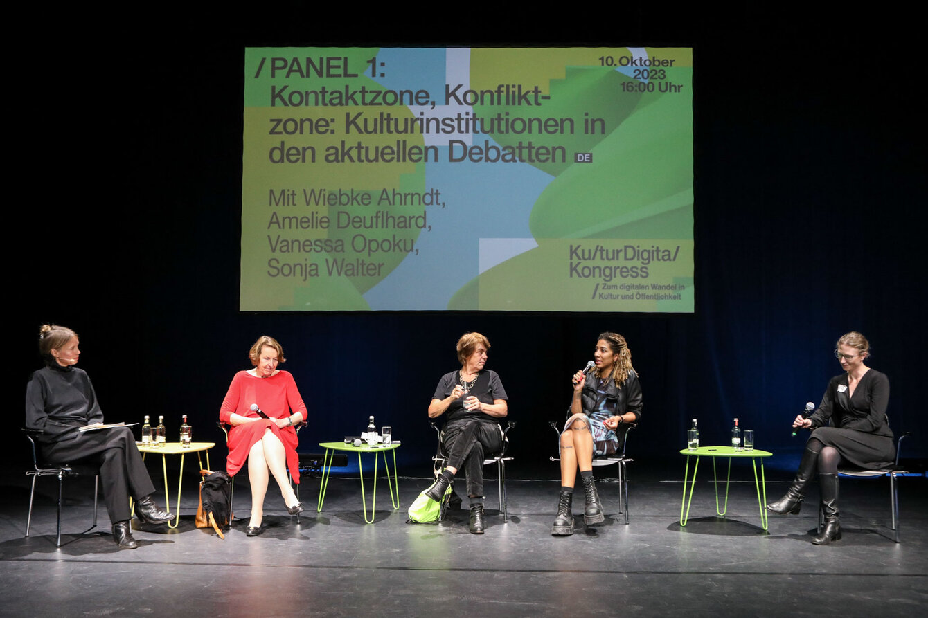 Panel discussion on a theater stage with 5 people