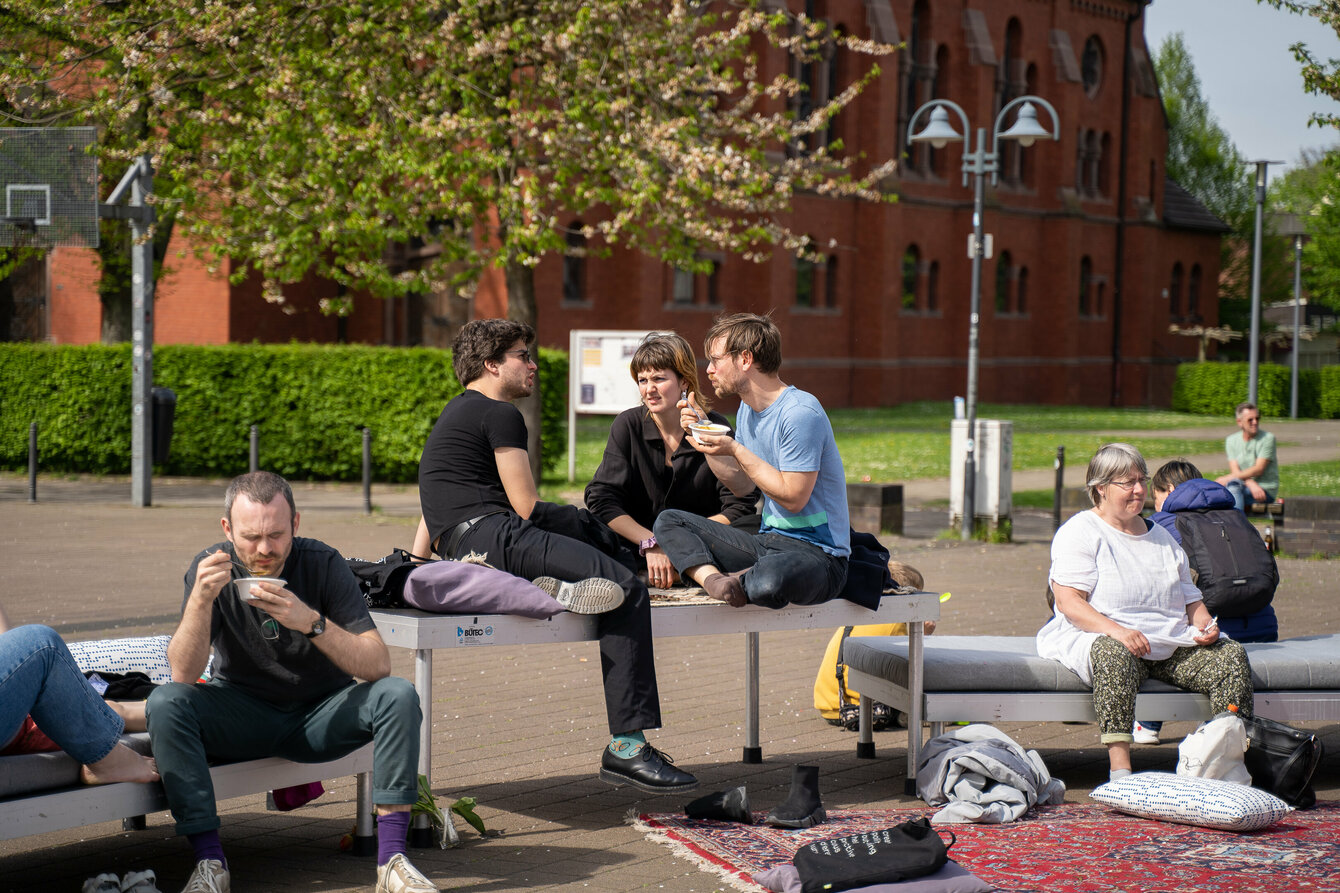 Menschen sitzen auf Loungemöbeln und essen Suppe