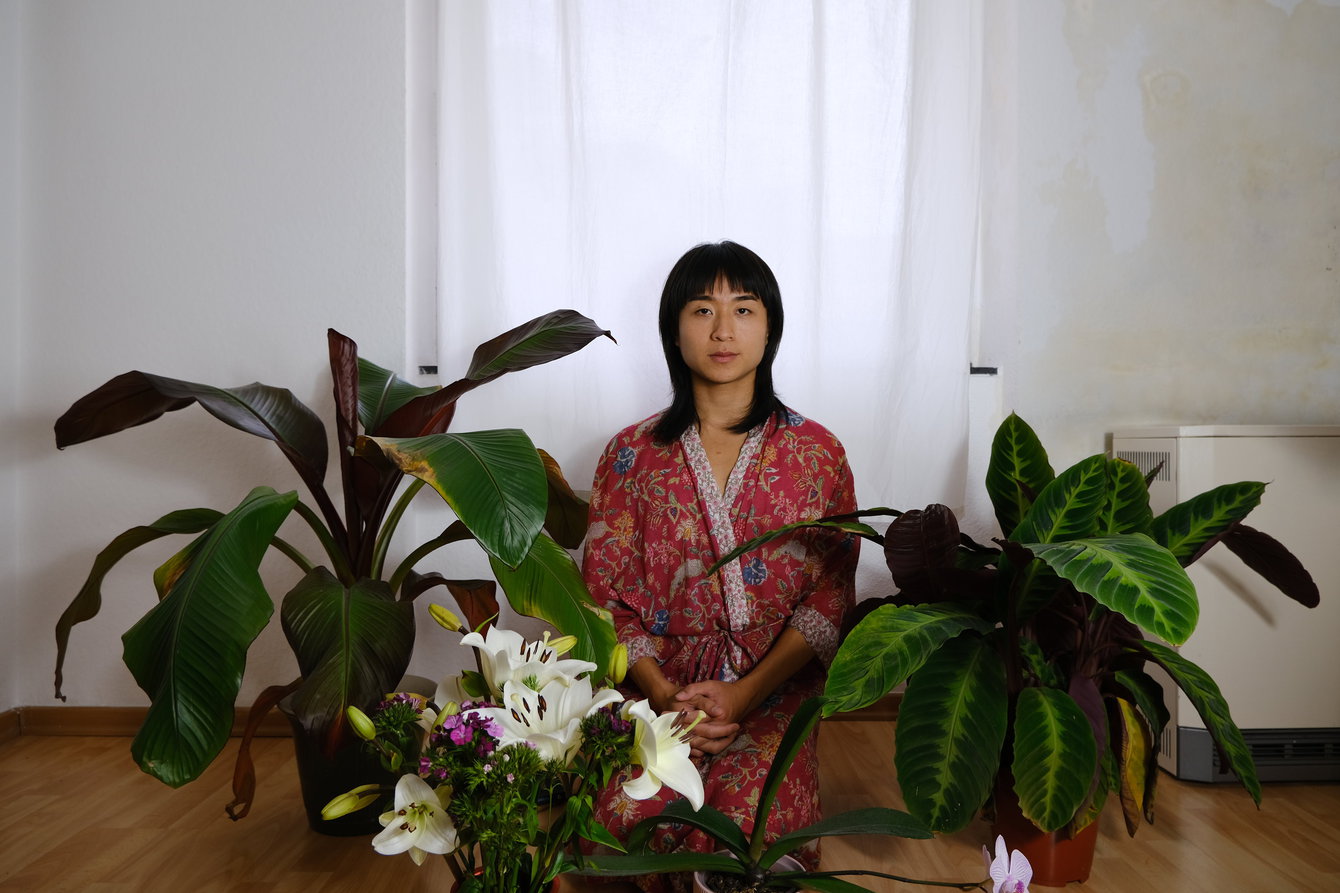 Paula Pau poses with her plants during her research while reading ›Earth Emotions: New Words for a New World‹ by Glenn Albrecht.