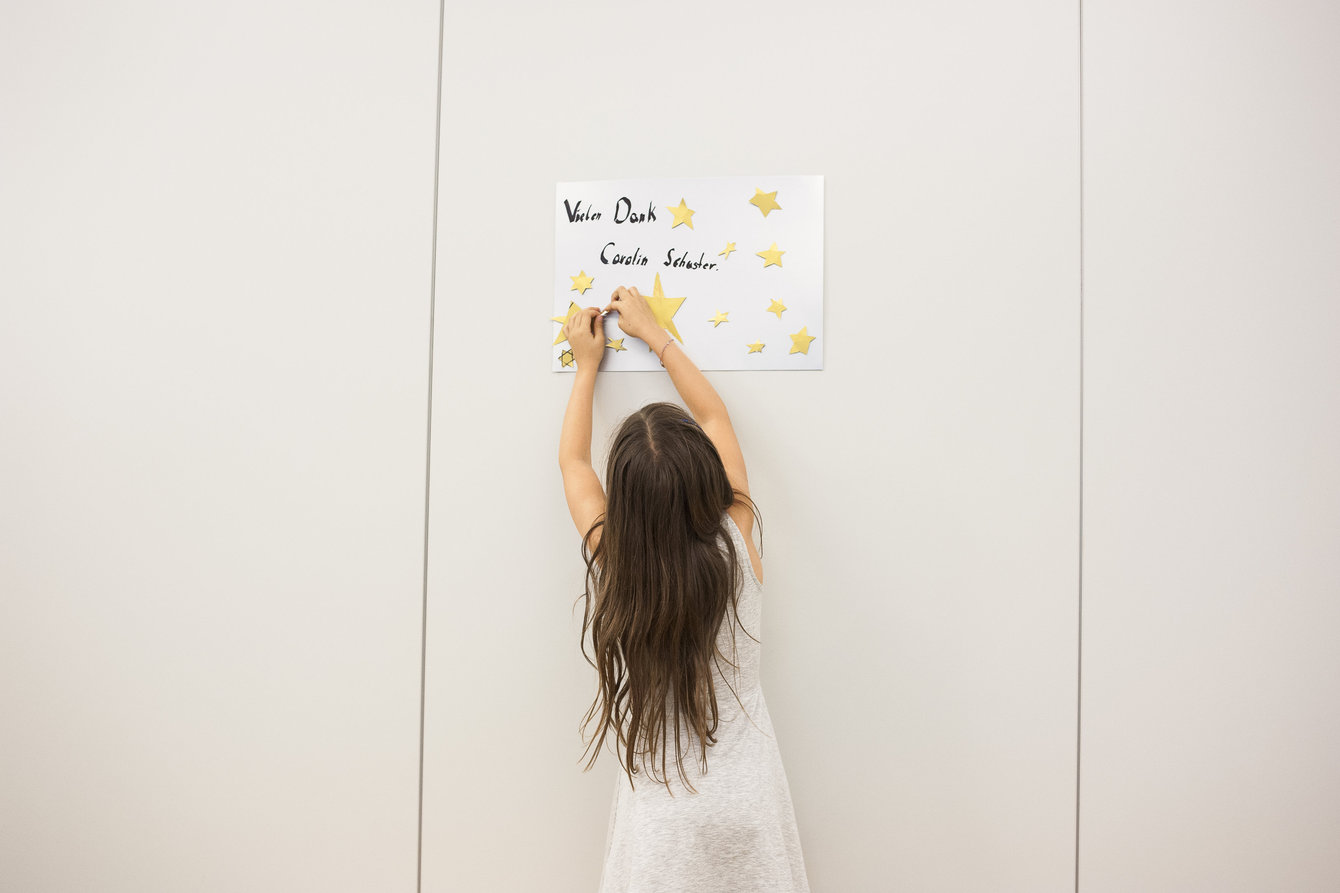 Ein Kind hängt ein Bild an die Wand