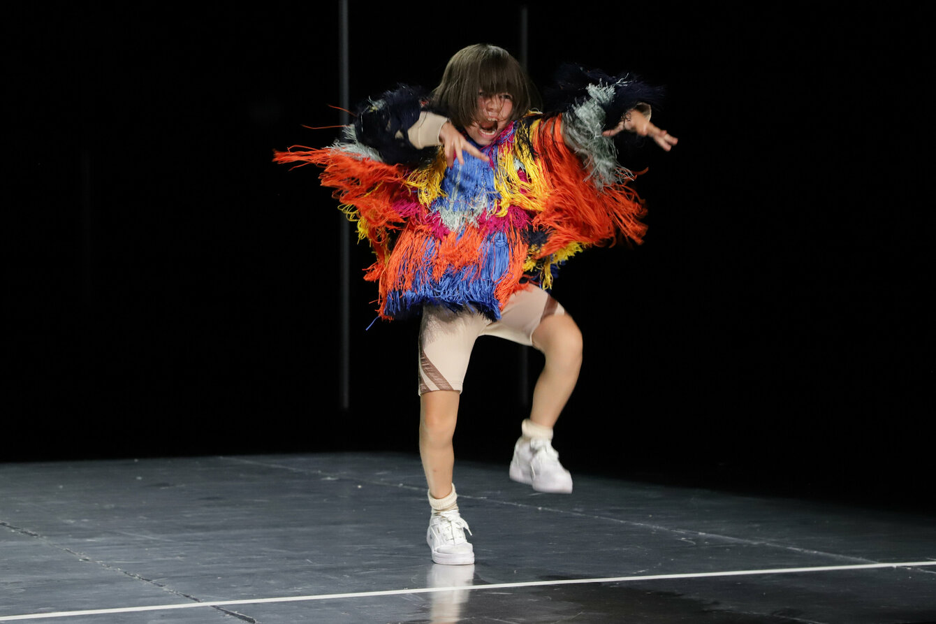 Ein tanzendes Kind mit einem Kostüm aus bunten Federn