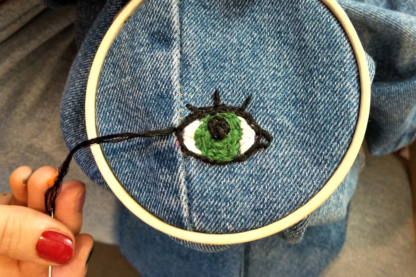 Eine Jean mit aufgesticktem Auge in einem Stickrahmen