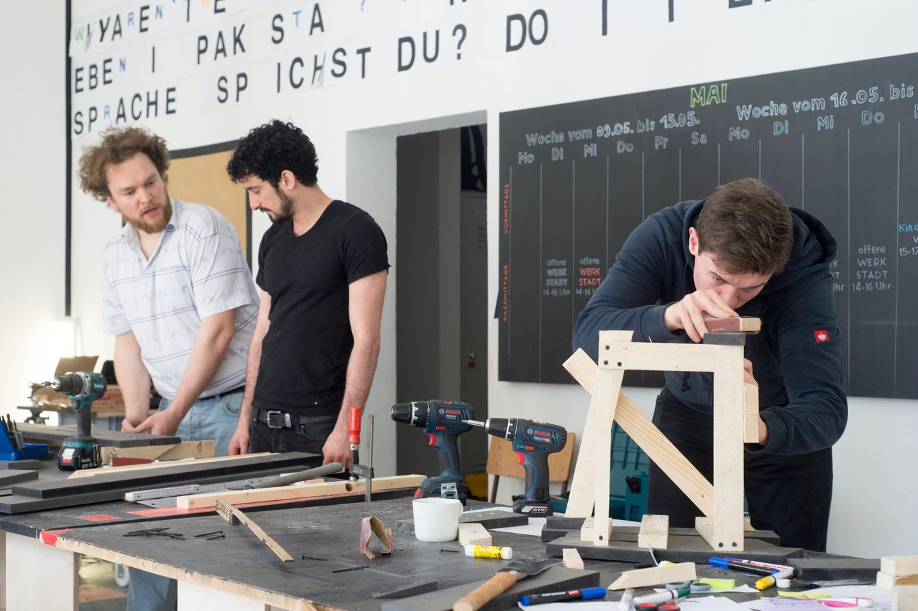 Drei Menschen bauen Elemente aus Holz in der WerkStadt