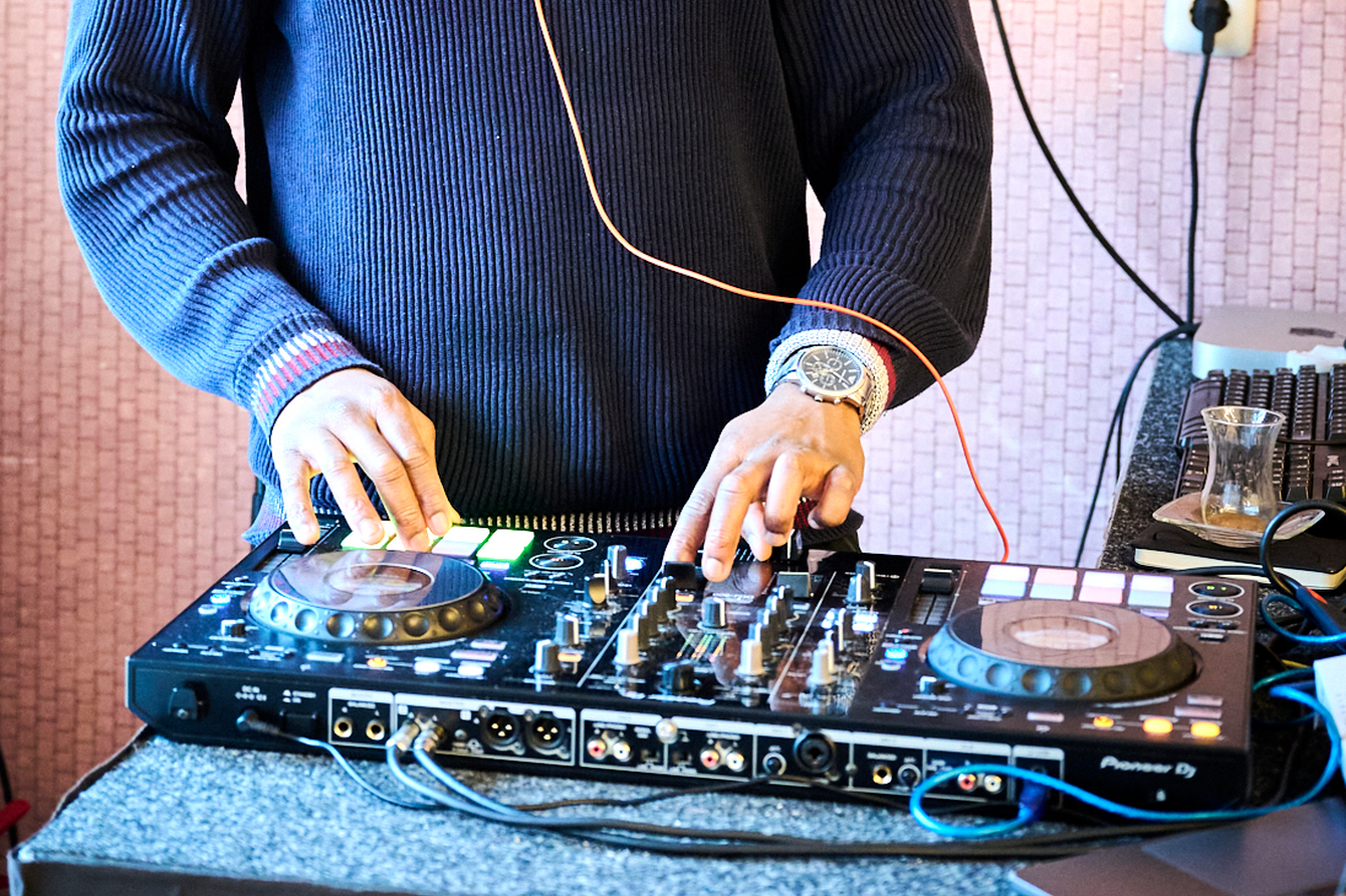 Eine Person legt am DJ-Pult auf. 