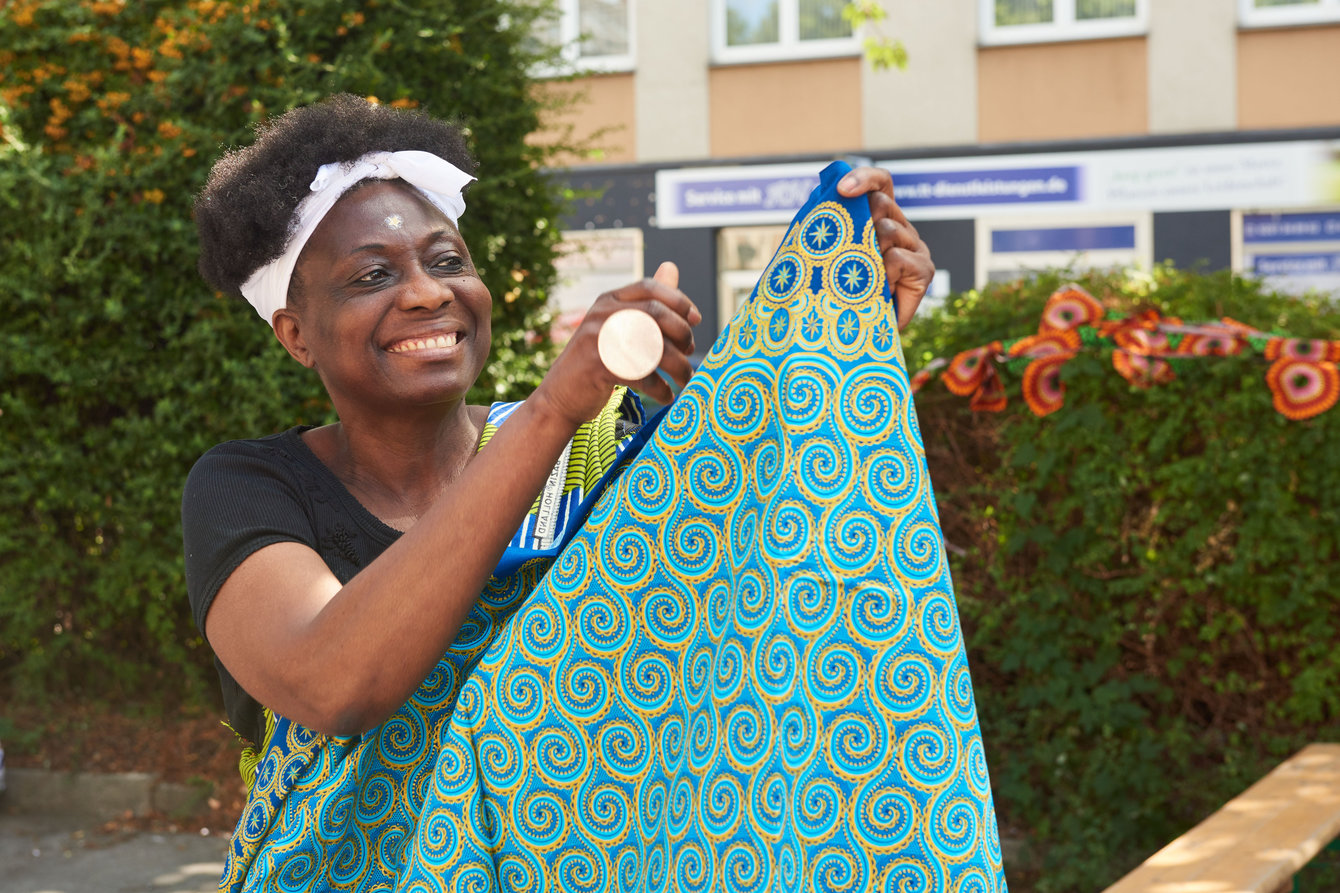 Künstlerin Clarisse Akouala mit einem Stück buntem Stoff in der Hand