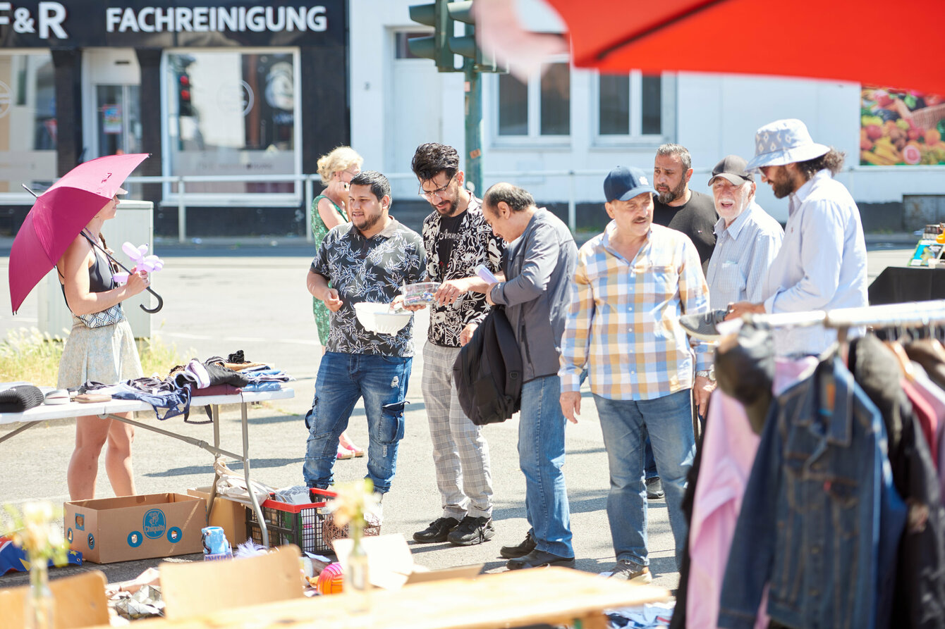 Mehrere Menschen stehen an einem Flohmarktstand