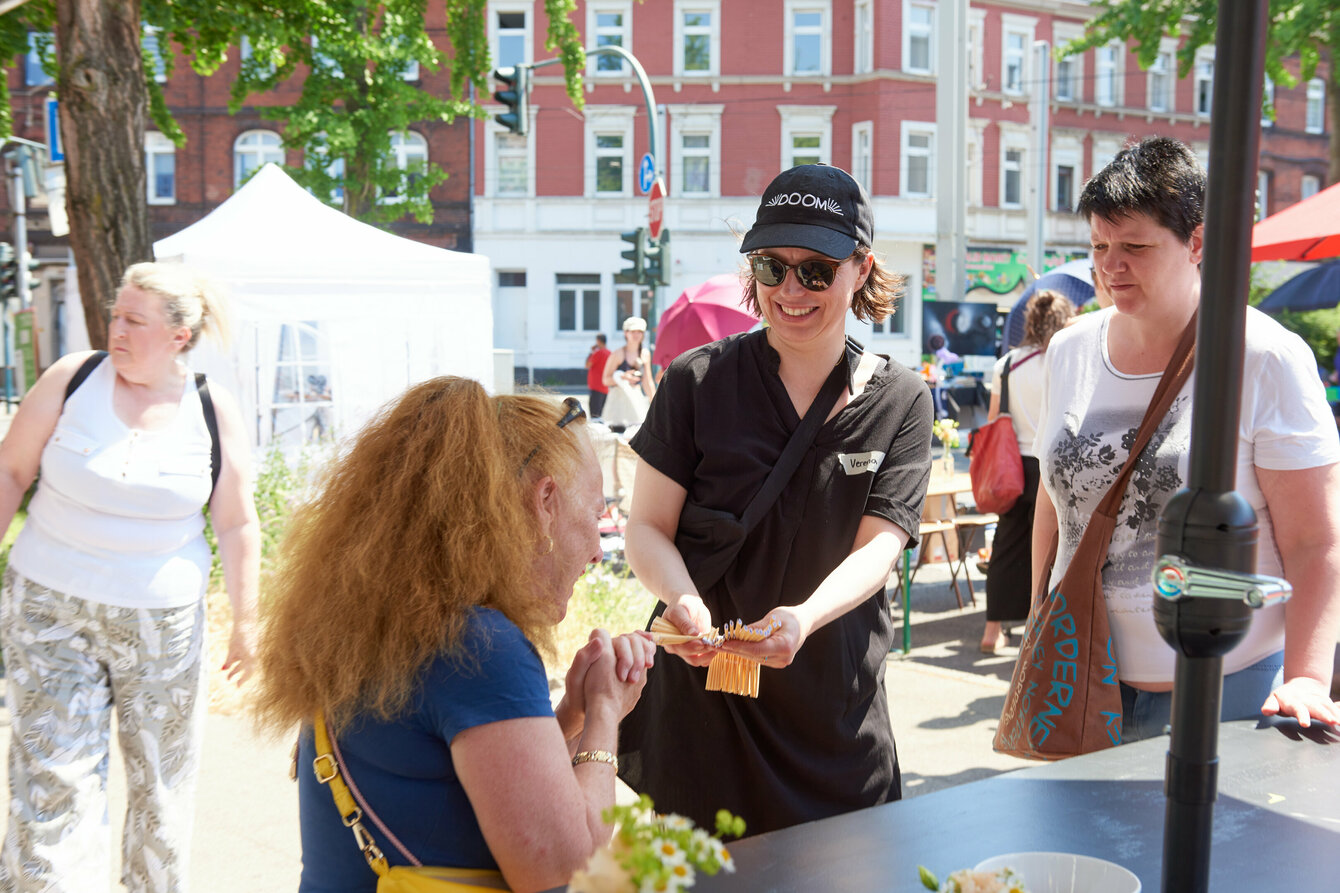 Menschen beim Flogmrkt, die gerade ein Los für die Tombola ziehen