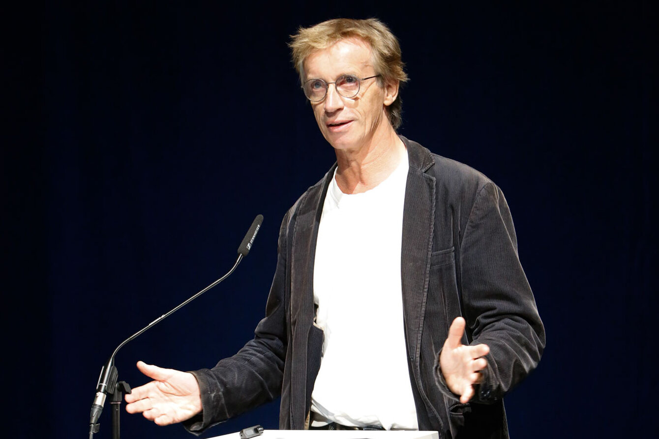 A man at a podium gives a speech while he gestures 
