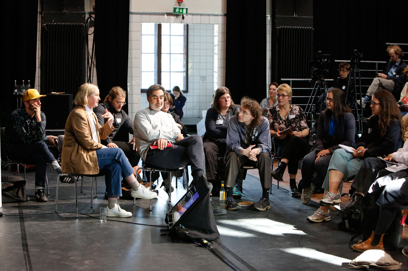 People sitting together in a group on a theater stage illuminated by sunlight