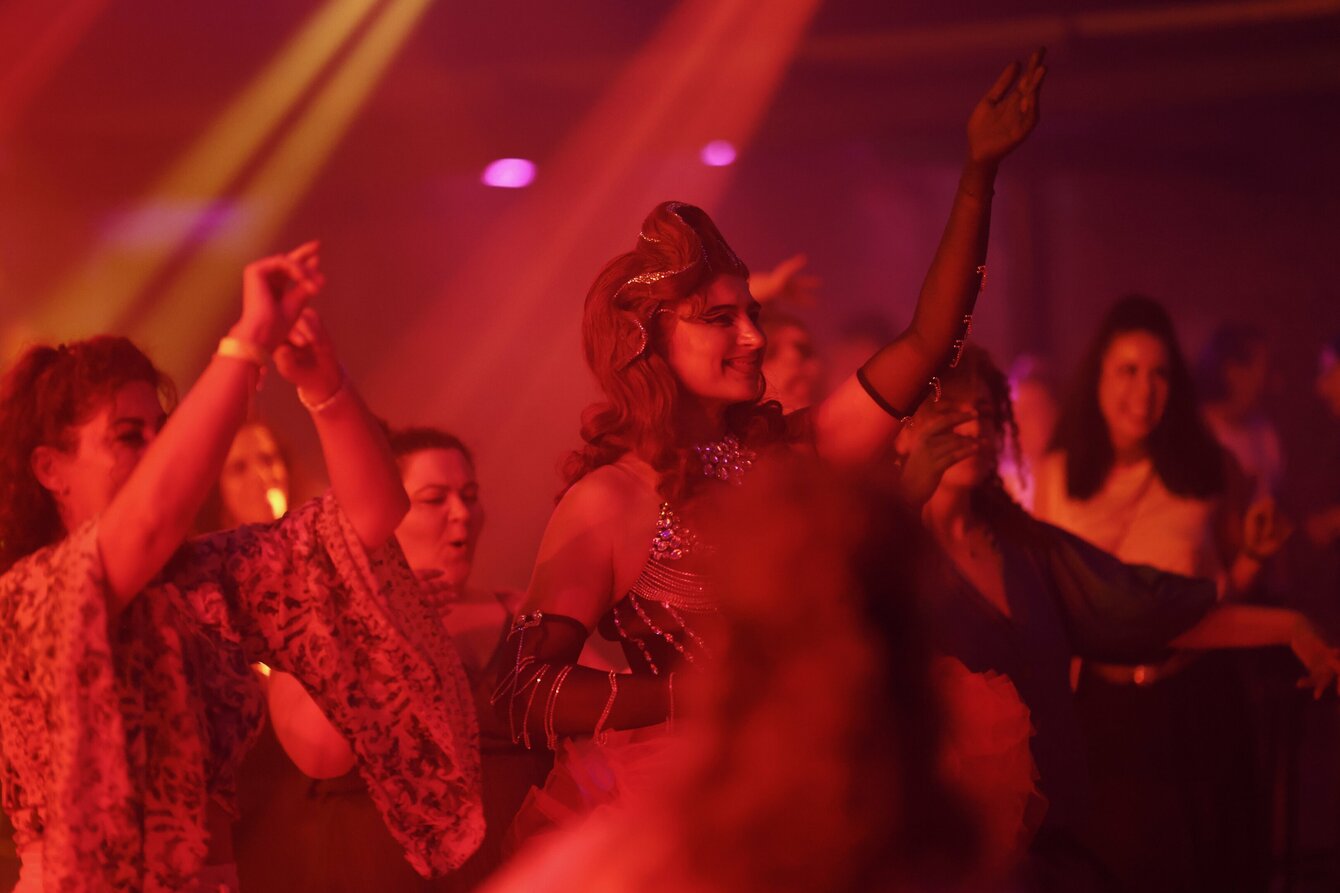 Momentaufnahme einer House of Namus-Veranstaltung. Das Foto zeigt eine Partysituation in einem Raum, der in rotes Licht getaucht ist. Alle tanzen, in der Mitte Prince Emrah.