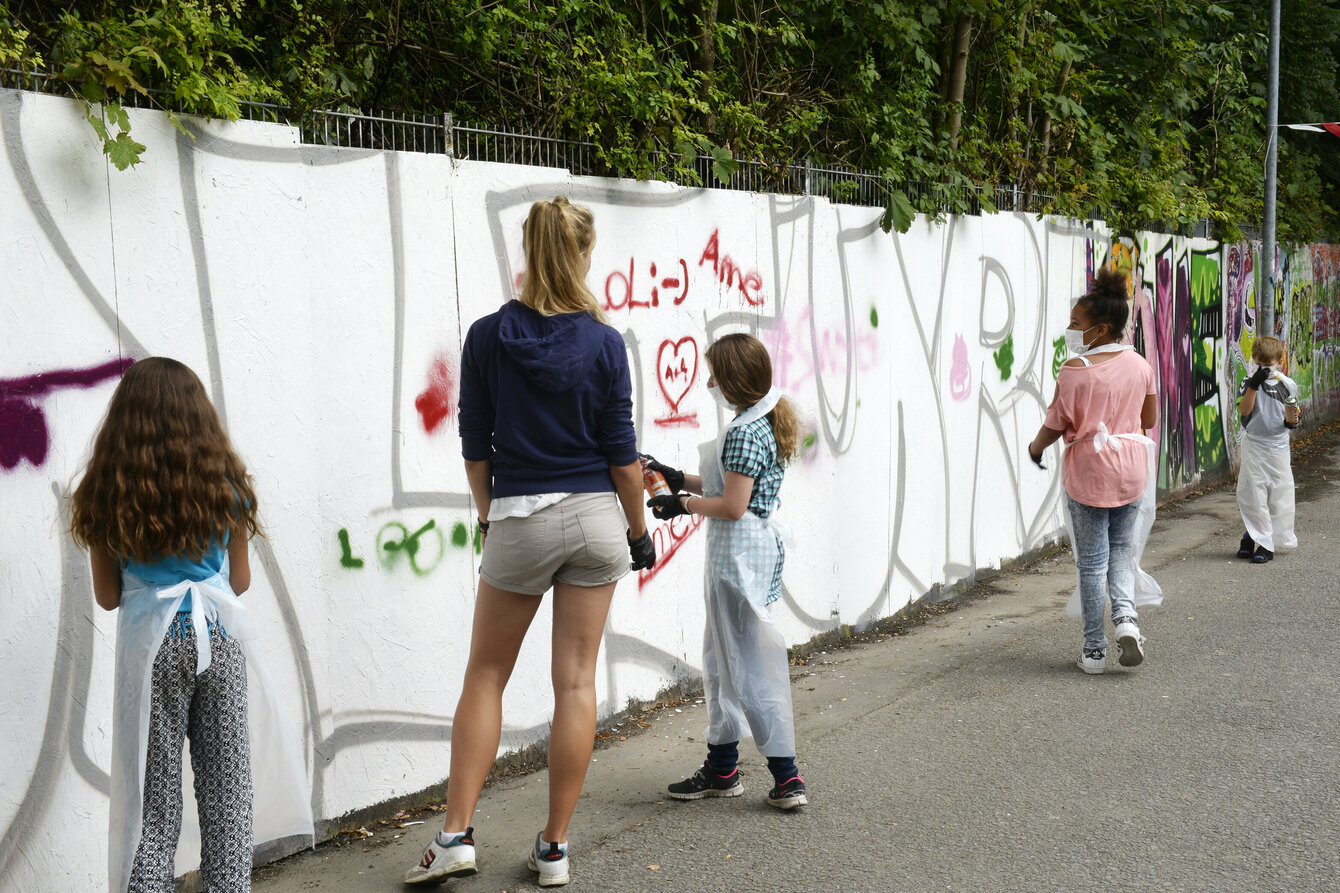 Ein junge malt Graffiti an eine Wand