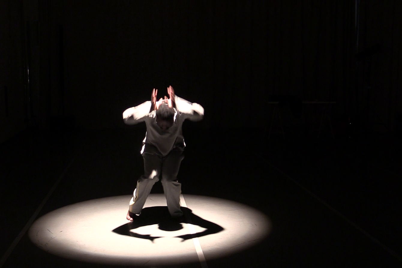 Koloto Siraji in einem weißen Anzug auf einer schwarzen Bühne im Lichtkegel