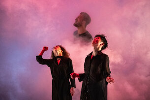 Drei Personen performen in pinkem Nebel