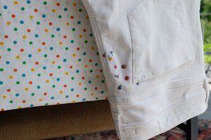 Eine weiße Jeans mit bunten Stickereien