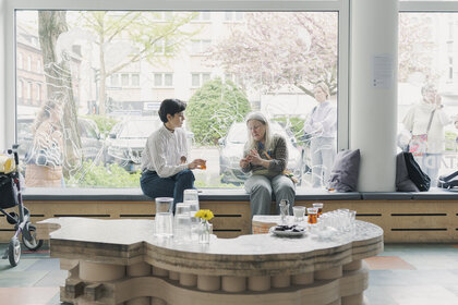 Zwei Personen sitzen im Schaufenster der WerkStadt