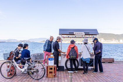 Personen an einer kleinen Verkaufsbude am Wasser