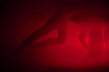 Eine Person in einer akrobatischen Pose und in rotes Licht getaucht