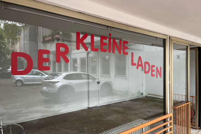 DIe Fensterfront des Kleinen Ladens. Auf den Fensterscheiben in roter Schrift der Text "Der Kleine Laden".