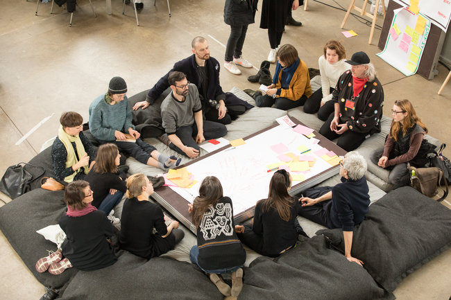 Studierende und Workshop-Teilnehmer:innen sitzen im Kreis