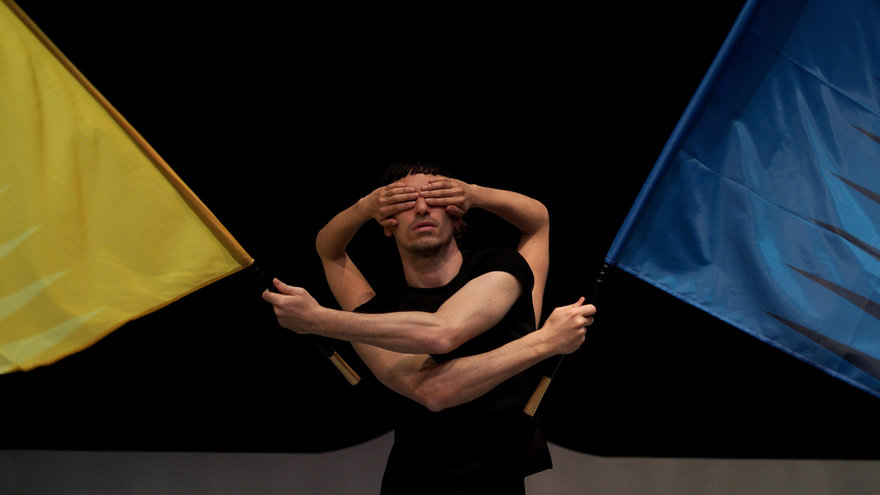 Tänzer:innen mit einer gelben und einer blauen Flagge auf der Bühne