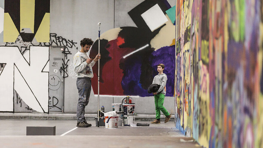 Zwei Personen stehen vor großen Wänden gefüllt mit Graffiti 